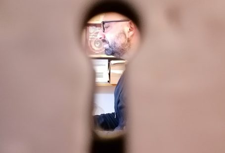Una fotografia in cui mi si vede attraverso il buco della serratura mentre sono impegnato a scrivere
