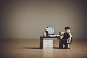 un omino di Lego seduto alla scrivania con un'espressione angosciata
