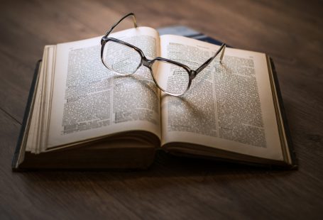 La foto di un libro aperto su un tavolo con degli occhiali sopra