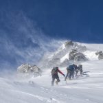 Una fotografia di un gruppo di scalatori che marcia in montagna sulla neve