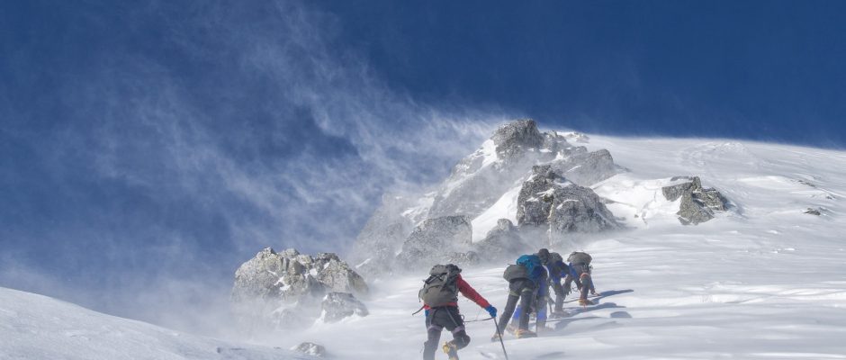 Una fotografia di un gruppo di scalatori che marcia in montagna sulla neve
