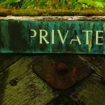 Un cartello di legno dipinto di verde attaccato su una staccionata con su scritto "private"